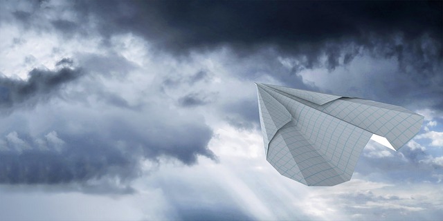 folded paper airplane flying in the sky. 