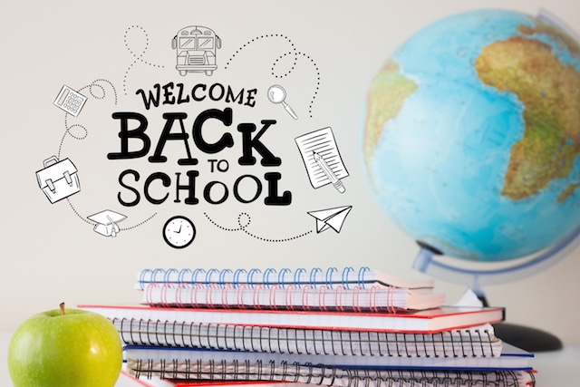 a welcome back to school sign with a globe, notebooks and apple. 